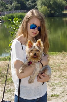 Happy young girl owner with yorkshire terrier dog walking in the park