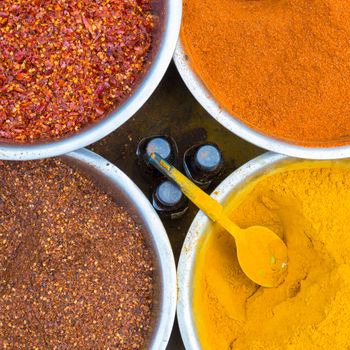 Oriental spices in white ceramic bowls beeing sold at local market. Food and cuisine ingredients. Colorful natural additives. Square composition.