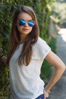 Beautiful smiling girl in white blouse, against green of summer park.