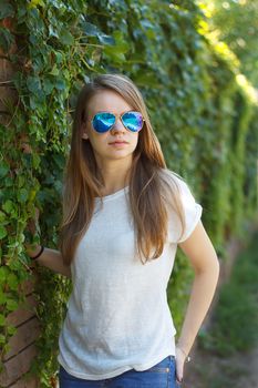 Beautiful smiling girl in white blouse, against green of summer park.