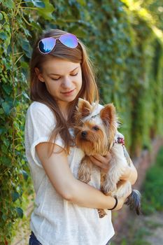 Happy young girl owner with yorkshire terrier dog walking in the park