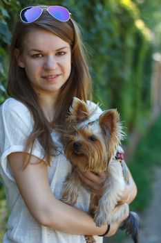 Happy young girl owner with yorkshire terrier dog walking in the park