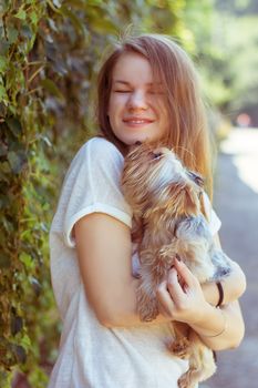 Happy young girl owner with yorkshire terrier dog walking in the park