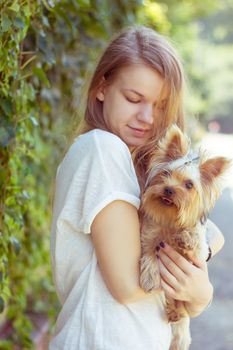 Happy young girl owner with yorkshire terrier dog walking in the park