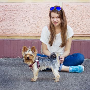 Beautiful sport woman sitting on the floor and holding Yorkshire terrier