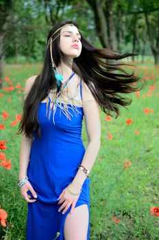 Brunette model wearing long blue dress with simple jewelry. Girl throwing her hairs aside.
