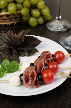 Appetizer of salami with mozzarella, olives, cherry tomatoes on skewers with basil