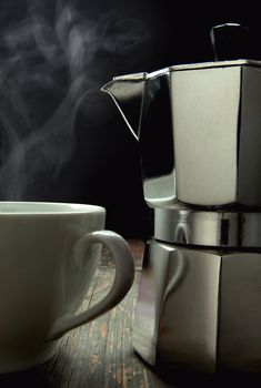 Closeup of an italian coffee maker next to a hot beverage 