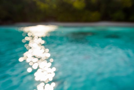Blur beach and green blue sea surface with reflecting sunlight evening in summer for background
