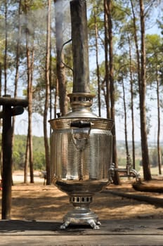 Old russian samovar outdoors with White smoke from the pipe of a samovar  .