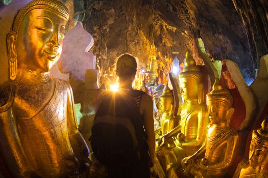 Woman among golden buddha statues in Pindaya Cave. Located next to the town of Pindaya, Shan State, Burma, Myanmar cave is Buddhist pilgrimage site and tourist attraction.