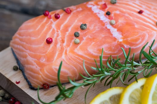 Raw Salmon Fish Fillet with Lemon, Spices and Fresh Herbs on Cutting Board
