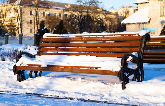 wooden bench covered with snow in the winter time