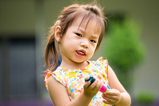 Outdoor portrait of sad little girl playing in summer park