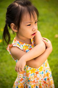 Outdoor portrait of sad little girl playing in summer park