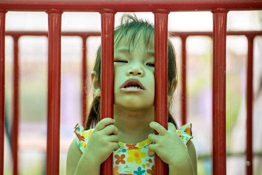 Outdoor portrait of sad little girl playing in summer park