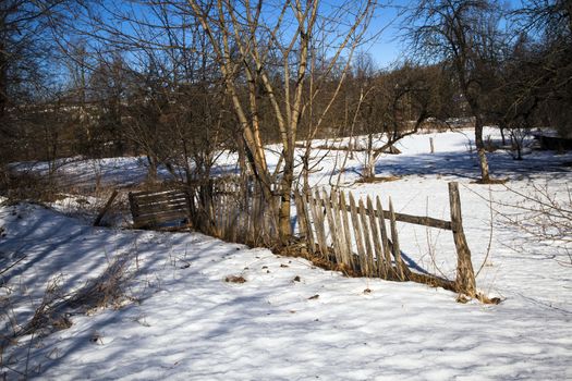   the old destroyed wooden fence in a winter season