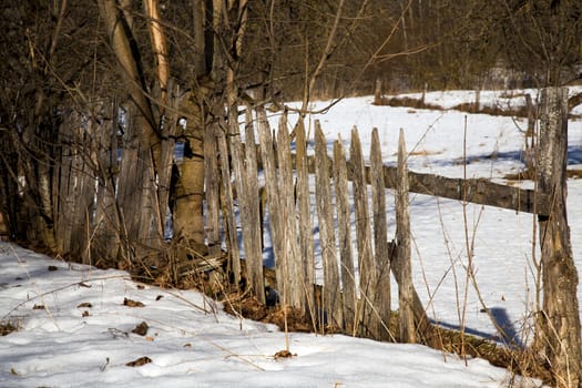  the old broken wooden fence in a winter season