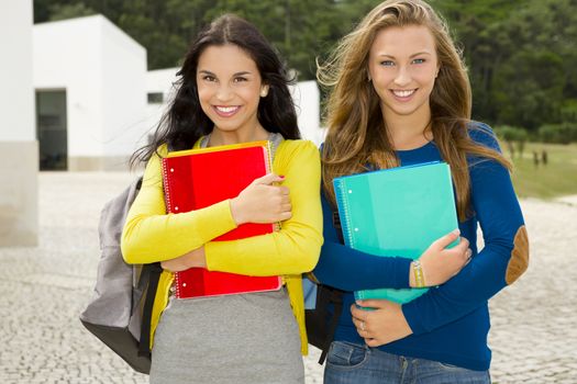 Two beautiful teenage students holding backpacks and smiling