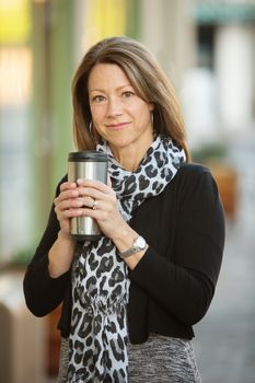 Cute businesswoman with aluminum coffee flask outdoors