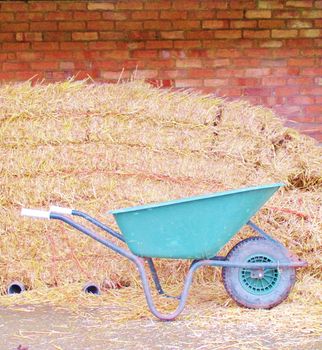 red Brick wall with hay bales and wheel barrow