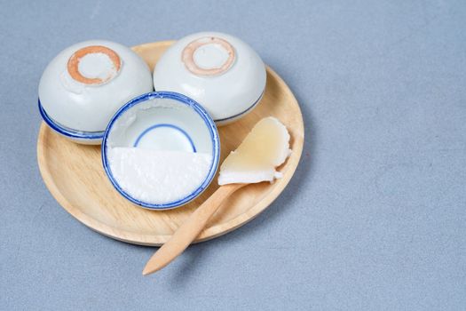 coconut milk custard in small porcelain cup (Thai dessert) in wooden dish on blue table.