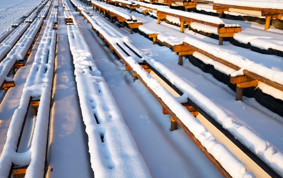   the old wooden benches covered with snow. old stadium, Belarus