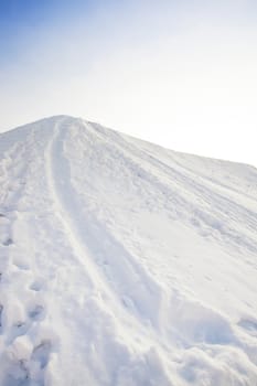   the small snow-covered hill covered with snow. on a slope there were traces from driving on a sled