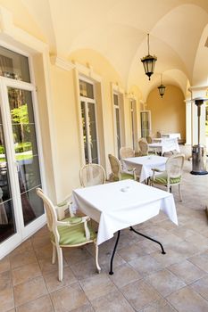   little tables and the chairs standing in cafe. are located on the street