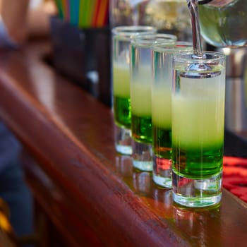 Layered cocktail Mexican green on the bar on the blur background.