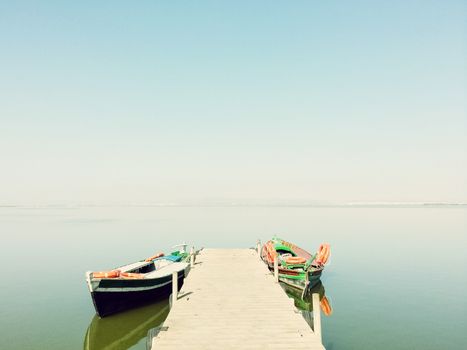 Calm lake with two fishing boats. Fresh water lagoon in Albufera de Valencia, Spain.