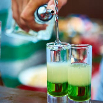 Layered cocktail Mexican green on the bar on the blur background.