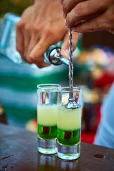 Layered cocktail Mexican green on the bar on the blur background.