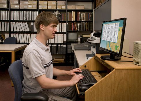 College student conducting computer research in a library archive. [Images on the computer screen were created for this photograph.]