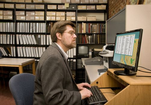 Researcher searching a computer database archives. [Images on the computer screen were created for this photograph. All titles and trademarks removed or obscured.]