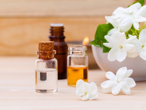 Aroma oil bottles arranged with jasmine flowers on wooden background .