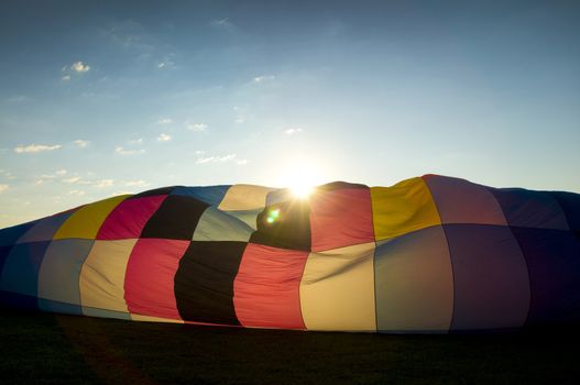 Sun peaking over the inflating envelope of a hot-air balloon