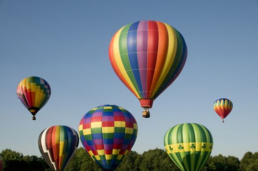 Various hot-air balloons with colorful envelopes ascending or launching at a ballooning festival