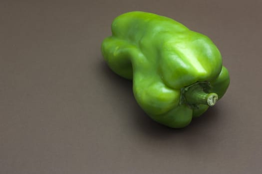 Green pepper isolated on a brown background to understand a concept to healthy eating