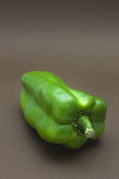 Green pepper isolated on a brown background to understand a concept to healthy eating