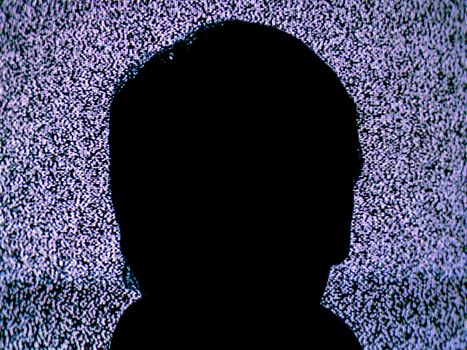 Image of a man's head in front of a static filled TV
