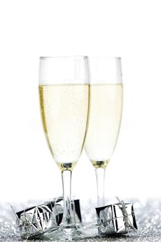 Glasses of champagne and christmas gifts on silver background