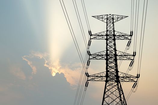 silhouette of high voltage electric tower with beautiful sunbeam  background