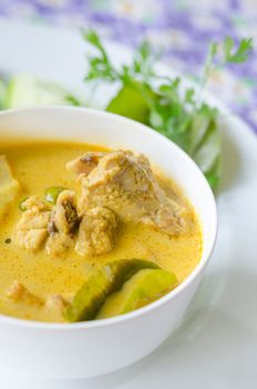 yellow chicken curry in bowl served with fresh vegetable
