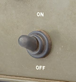 closed up old black toggle switch on green surface - on