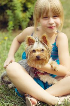 Girl 6 years old on the grass holding a Yorkshire Terrier