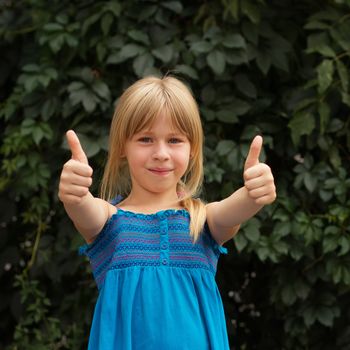 Laughing girl with daisy in her hairs, showing thumbs up