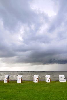 Some beach chairs on the coast of the North Sea in Germany at stormy weather.