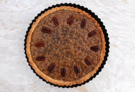Pecan pie fresh from the oven on a marbled kitchen work surface
