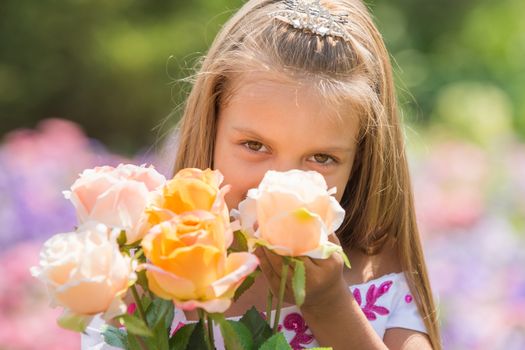 Happy six year old girl in a lush evening pink dress walking through the green garden